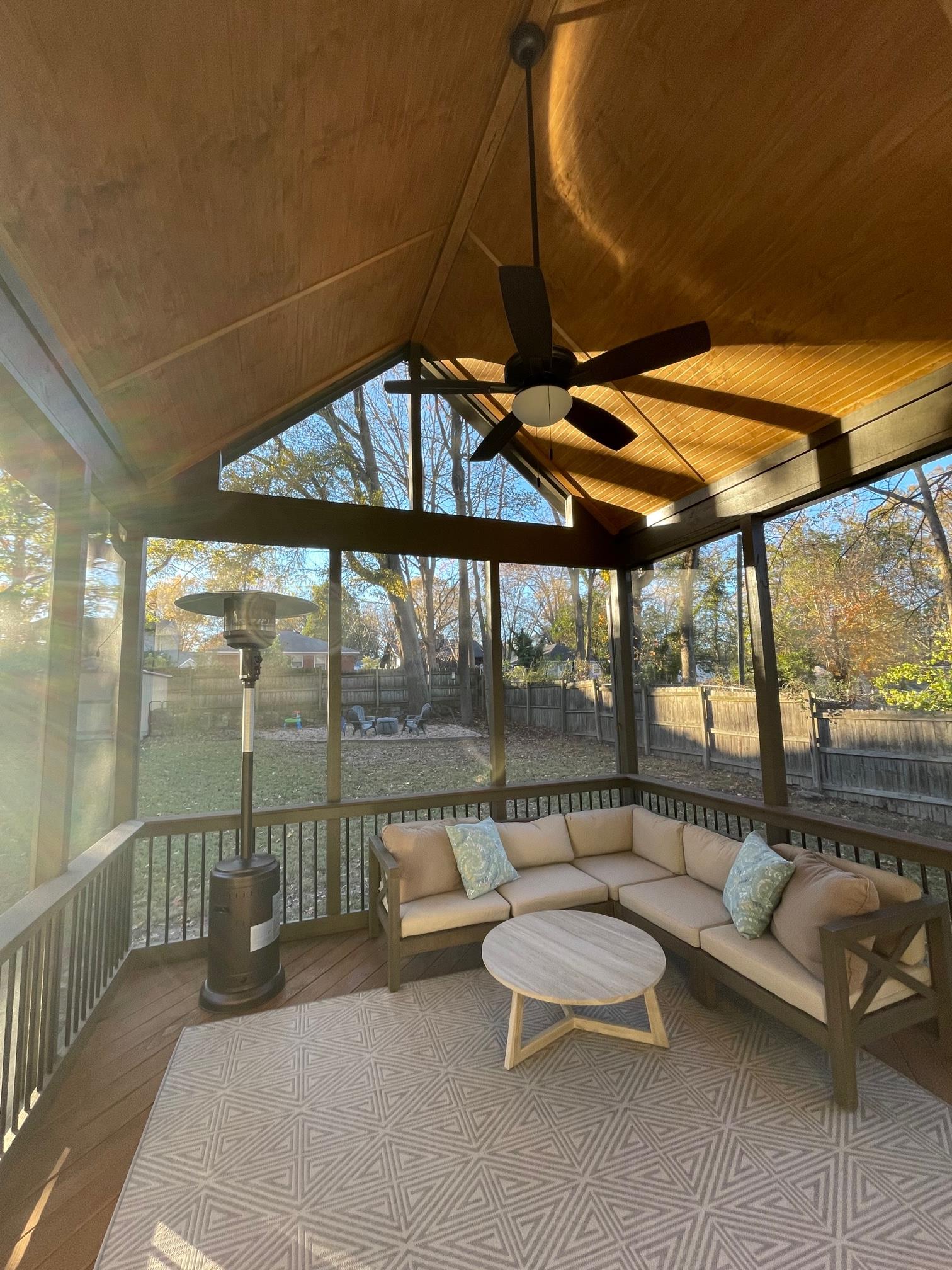 A cozy screened porch in Charlotte, NC, with a sectional sofa, rug, and a portable heater.
